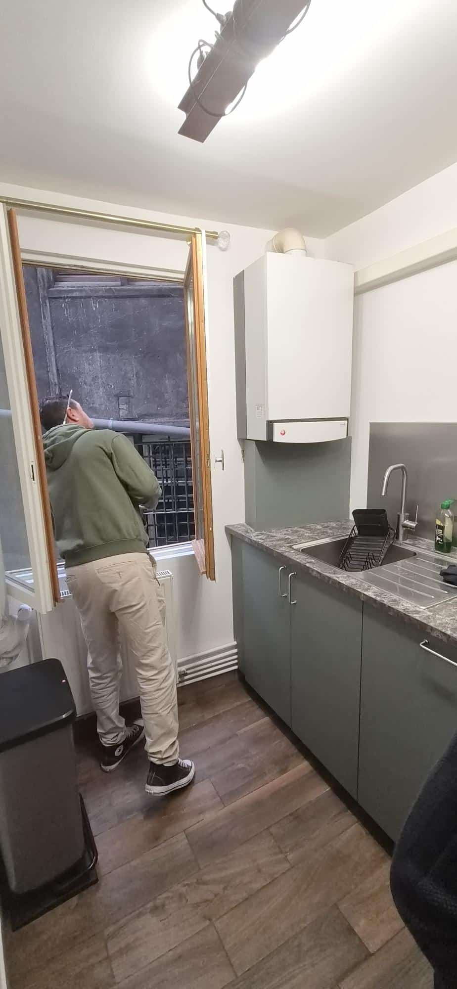 Stagiaire repérant les conduits en façade depuis la fenêtre lors d'une mise en situation DPE